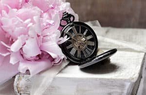 a pocket watch and flower on a book